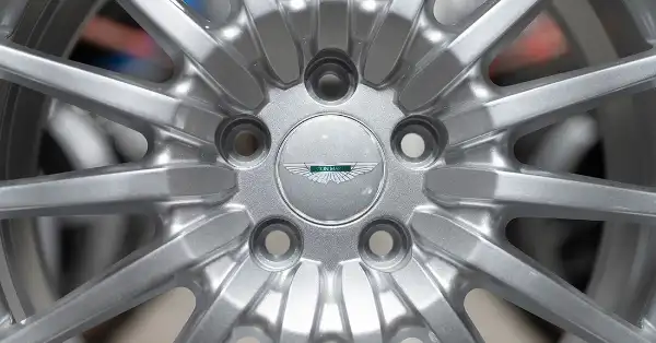 Close-up of 16-spoke Aston Martin DB9 original wheel with center cap.