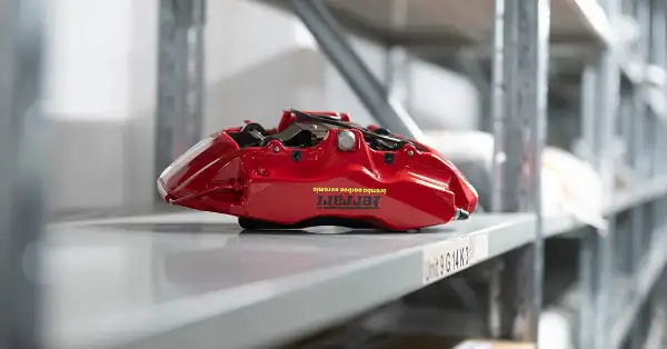Ferrari red Brembo brake calliper on storage shelf inside Eurospares warehouse.