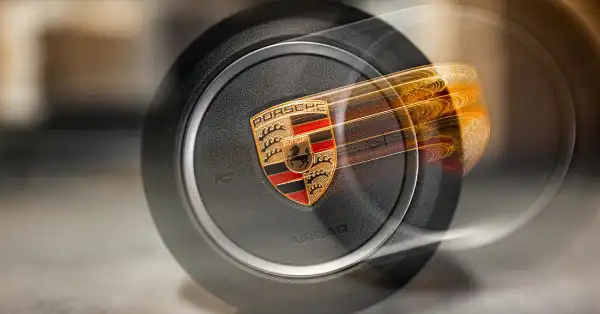 Porsche steering wheel airbag with detailed Porsche crest in a close up motion blur effect.